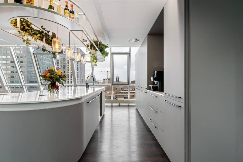 Colliers Rotterdam: lichte pantry met ronde bar en plantenrek, met uitzicht op de stad
