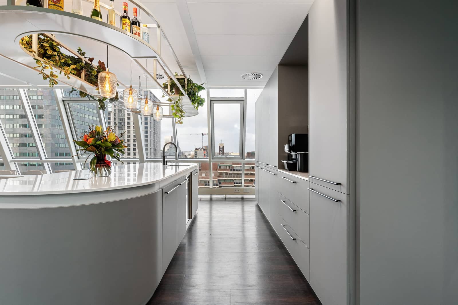 Colliers Rotterdam: lichte pantry met ronde bar en plantenrek, met uitzicht op de stad